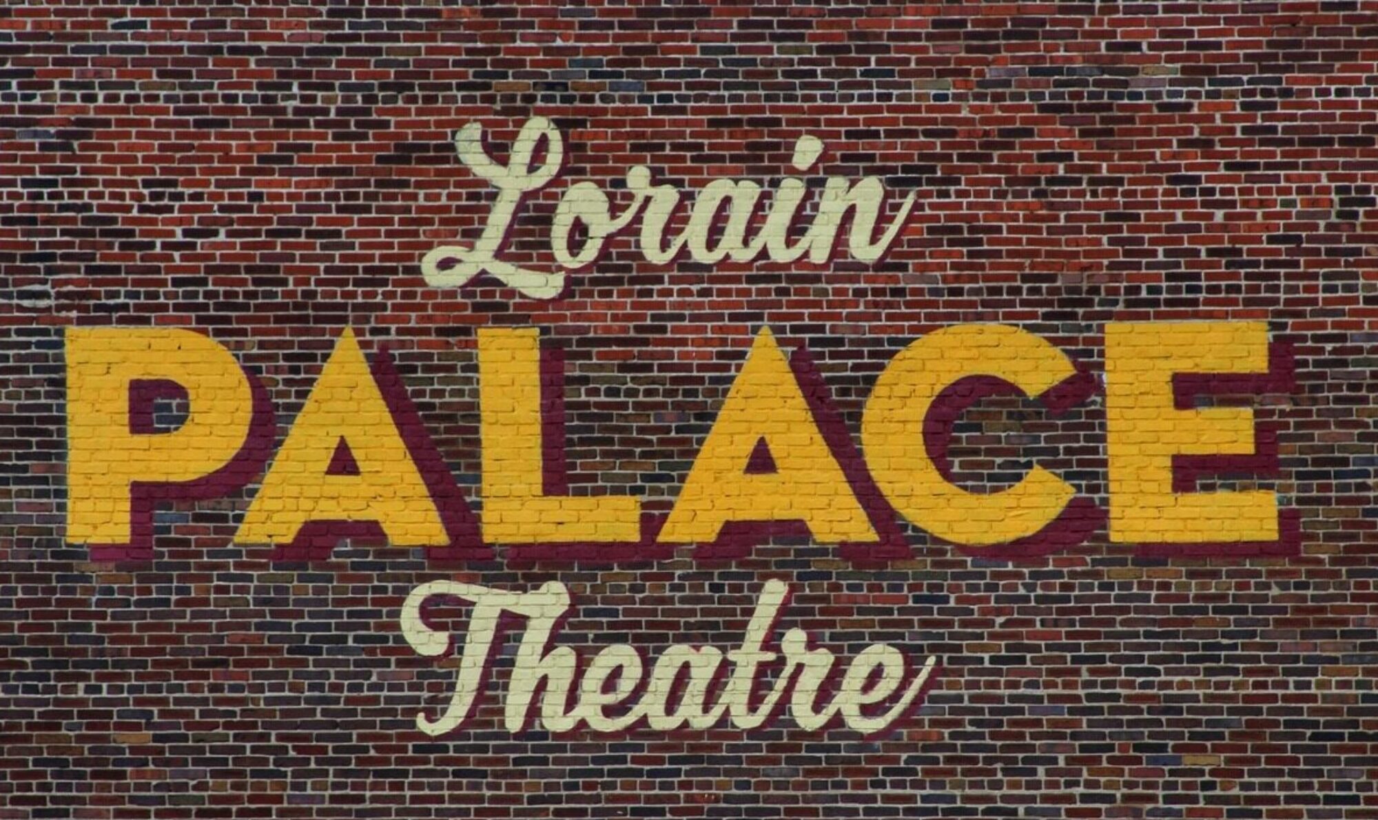 A brick wall with the words lorain palace theatre written in yellow.
