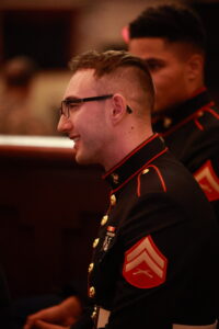 A man in uniform smiles while standing next to another man.
