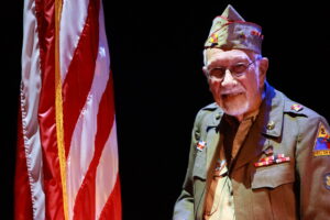A man in uniform standing next to an american flag.