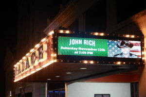 A large sign is lit up on the side of a building.