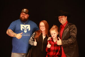 A family posing for the camera in front of a black background.