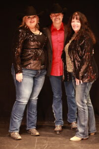 Three women posing for a picture on stage.