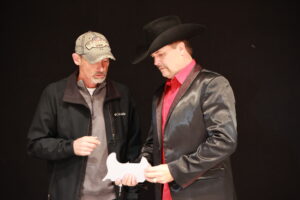 Two men in cowboy hats and jackets are standing.