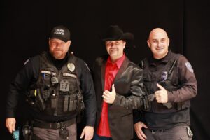 Three men in police uniforms and one man wearing a red shirt.