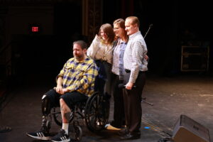 A man in a wheelchair with three people standing around him.