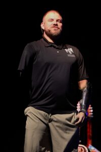 A man with a beard and black shirt holding something