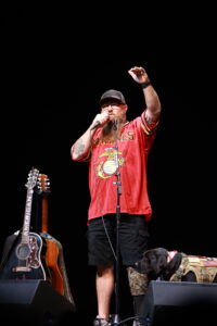 A man with long hair and beard holding a microphone.