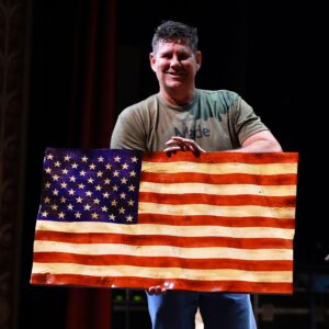 A man holding an american flag painted on the side of his body.