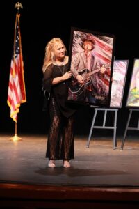 A girl holding up an image of a man in cowboy hat.
