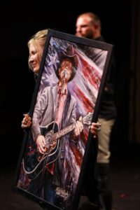 A person holding up a picture of a man with a guitar.