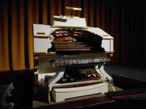 A small white organ in front of a curtain.